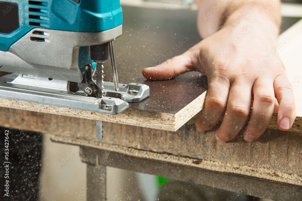 Close-up carpenter working with an electric jigsaw Close-up carpenter working with an electric jigsaw