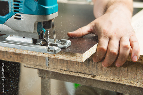 Close-up carpenter working with an electric jigsaw