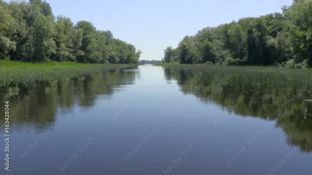 The picturesque river landscape. Video from the nose of the ship sailing. Clear blue sky and calm water of the river. The reeds and the green trees on the banks. Footage clip 4k, UHD, Ultra HD The picturesque river landscape. Video from the nose of the ship sailing. Clear blue sky and calm water of the river. The reeds and the green trees on the banks. Footage clip 4k, UHD, Ultra HD