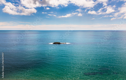 Fototapeta Naklejka Na Ścianę i Meble -  Single rocky island on calm azure blue sea.