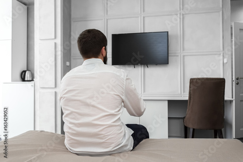 Young man using TV remote control
