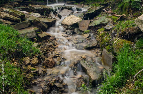 stream flowing through rocks with grass on the banks, background, landscape