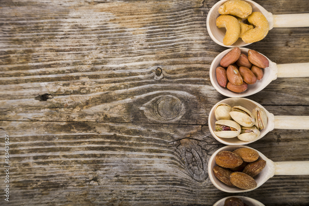 Nuts in a wooden spoons on a  wooden table.