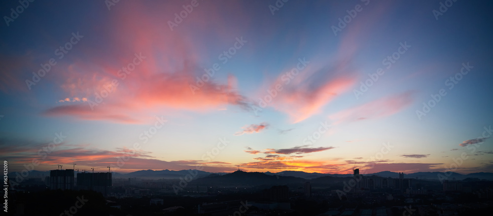 Beautiful panorama natural sunset sunrise over silhouettes city skyline and amazing orange cloud blue sky above it .