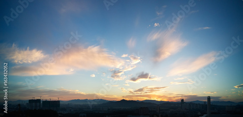 Beautiful panorama natural sunset sunrise over silhouettes city skyline and amazing yellow cloud blue sky above it .