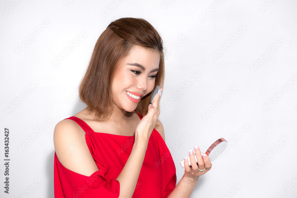 Beautiful asian woman standing red dress and holding cosmetic product.