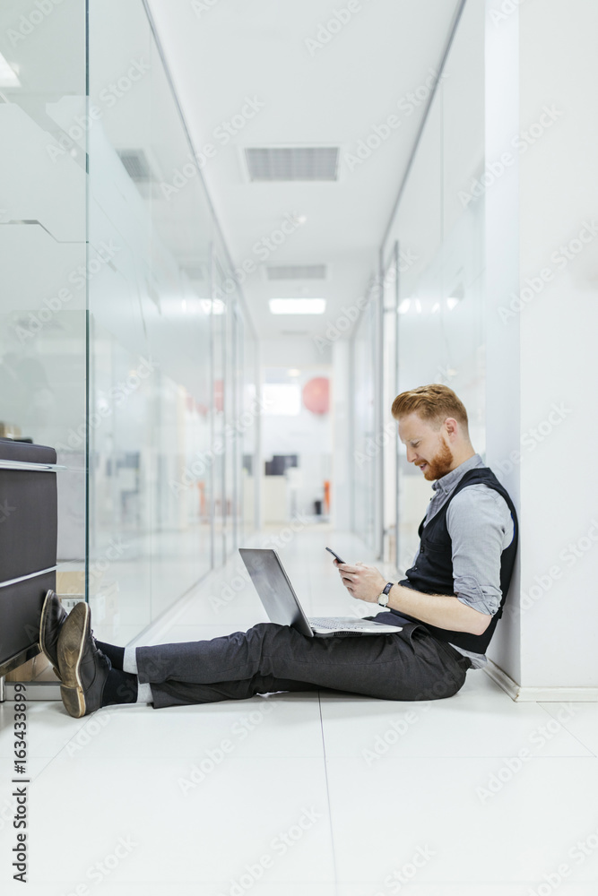 Businessman in office sitting on floor, using laptop Businessman in office sitting on floor, using laptop