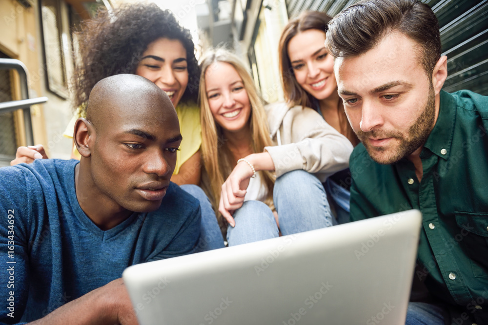 Multi-ethnic group of young people looking at a tablet computer Multi-ethnic group of young people looking at a tablet computer