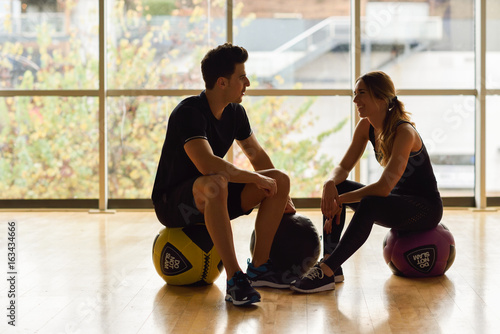 Man and Woman sitting with fitballs in the gym.