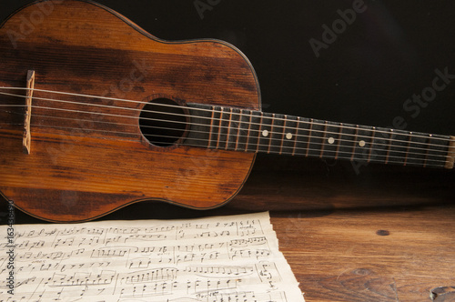 Ancient little acoustic guitar and hand-written notes on the table
