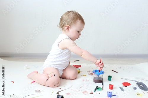 happy little 1 year baby girl painting at home