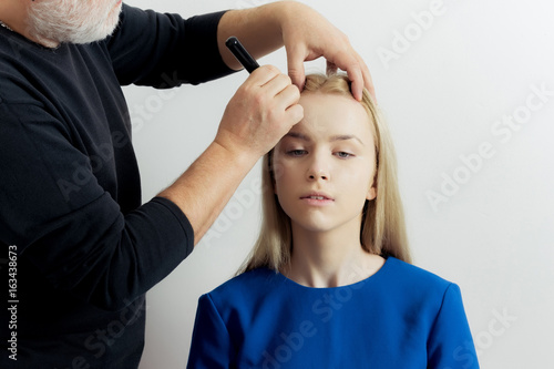 Girl getting makeup on face skin with powder brush