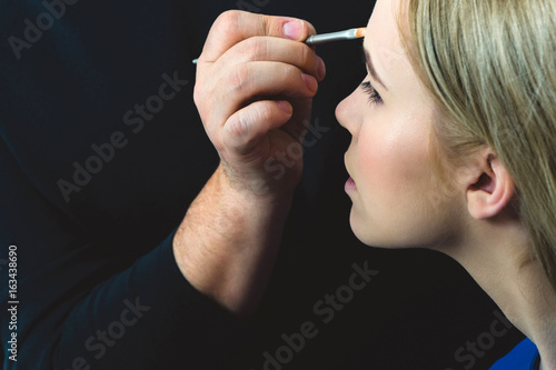 Girl getting makeup on face skin with powder brush