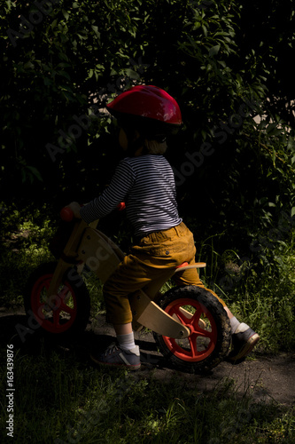 Child driving into the shadow on his bike