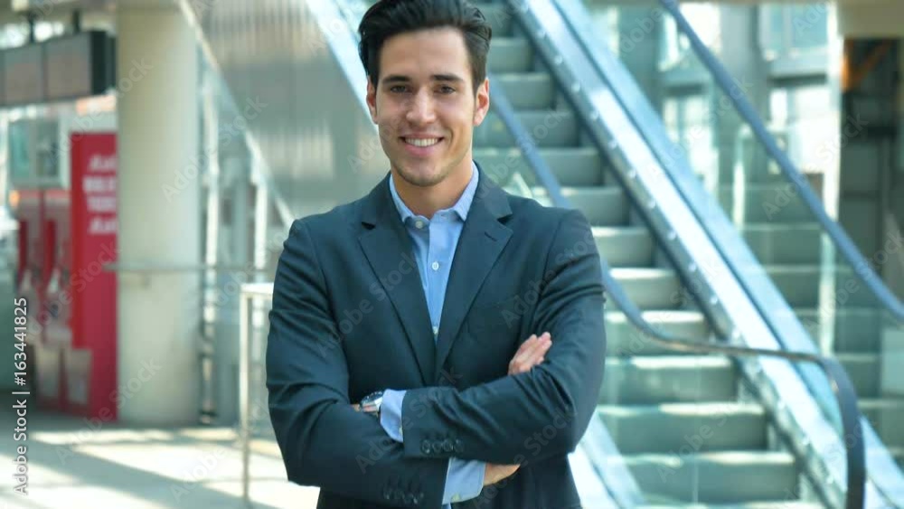 Portrait of a young handsome businessman in suit, at the station, leading business affairs, smiling, background with an escalator. Concept: new business, business relationships, career growth, success Portrait of a young handsome businessman in suit, at the station, leading business affairs, smiling, background with an escalator. Concept: new business, business relationships, career growth, success