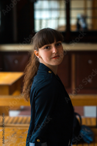 A girl in a business suit is sitting near the window. photo