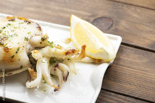 Cuttlefish with garlic and parsley and lemon on wooden table.