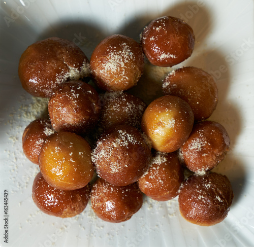Top view of a Greek loukoumades donuts with honey and cinnamon close-up on a white plate. horizontal view from above