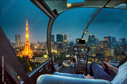Helicopter flying on Tokyo Skyline at dusk with illuminated Tokyo Tower, icon and landmark of Minato Distric in Tokyo, Japan.