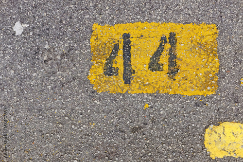 Yellow imprint of the number forty-four on an asphalt pavement.