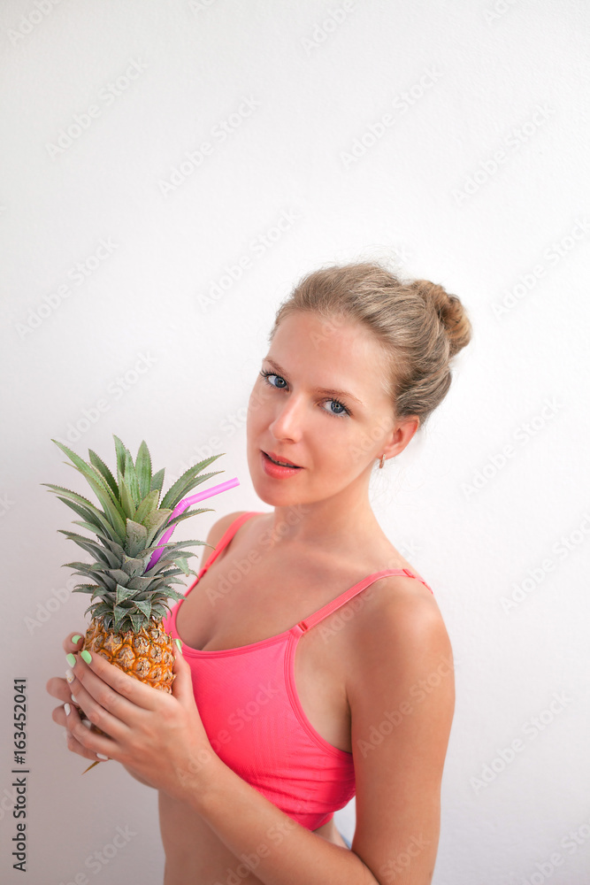 Portrait of a pretty young summer girl holding pineapple isolated over background. Concept of a healthy lifestyle. Portrait of a pretty young summer girl holding pineapple isolated over background. Concept of a healthy lifestyle.
