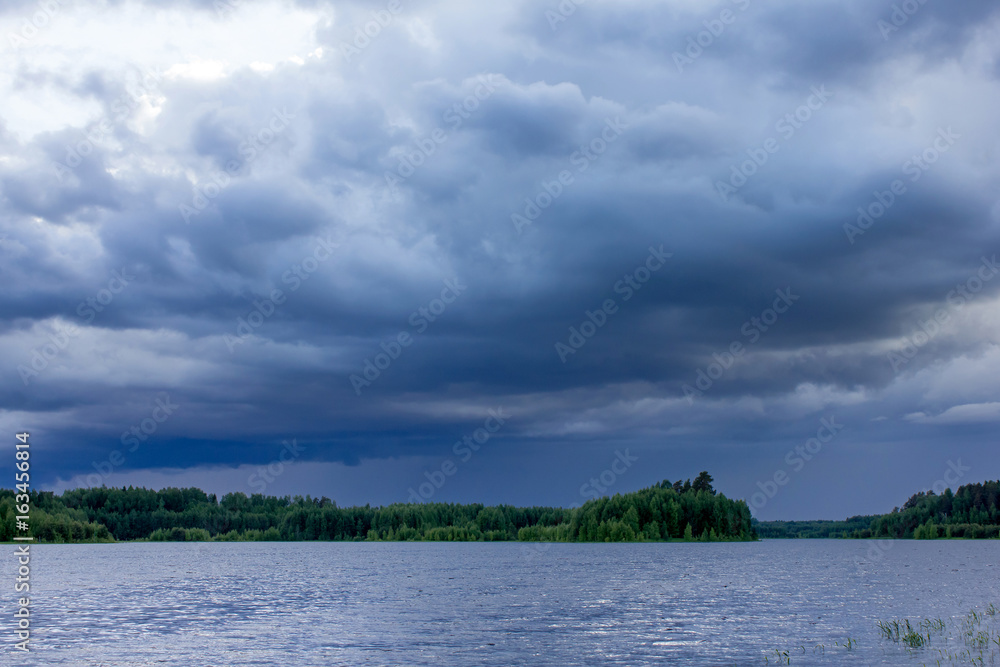 Dark blue storm cloud over the forest lake Dark blue storm cloud over the forest lake