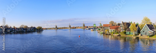 Panorama of wooden houses and windmills framed by the blue River Zaan, Zaanse Schans, North Holland, The Netherlands photo