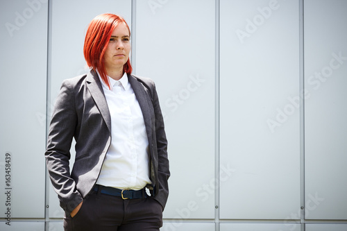 Serious successful red-haired girl boss, businesswoman in suit, with space for text and advertising photo