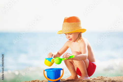 Happy child is playing with toys at sea shore background.