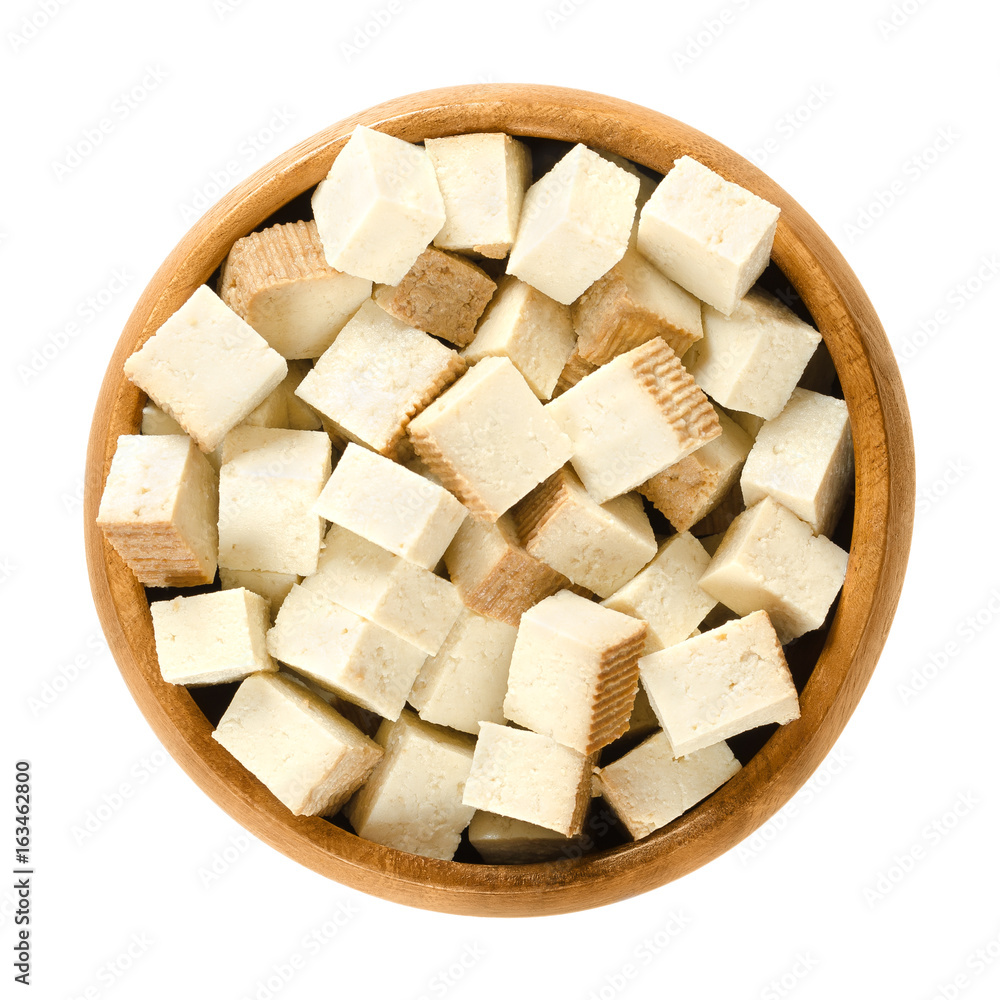Smoked tofu cubes in wooden bowl. Bean curd. Coagulated soy milk, pressed into firm white blocks. Component of Asian cuisine. Meat substitute. Isolated macro food photo close up from above over white Smoked tofu cubes in wooden bowl. Bean curd. Coagulated soy milk, pressed into firm white blocks. Component of Asian cuisine. Meat substitute. Isolated macro food photo close up from above over white