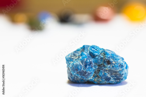 Precious stones - Blue Apatite crystal (on white) with colourful gems in the background