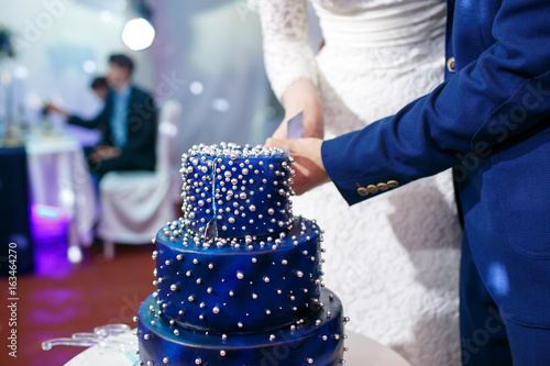 Foto Bride and groom cut blue wedding cake.
