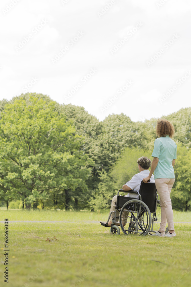 Obraz premium Young nurse with senior woman in middle of the garden