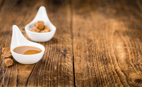 Portion of Caramel Sauce on wooden background (selective focus)