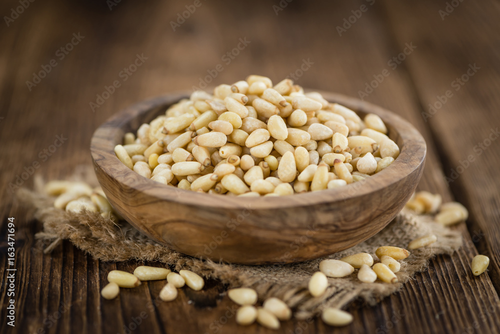 Portion of Pine Nuts on wooden background (selective focus) Portion of Pine Nuts on wooden background (selective focus)