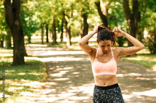 Fit female athlete tying hair before her workout