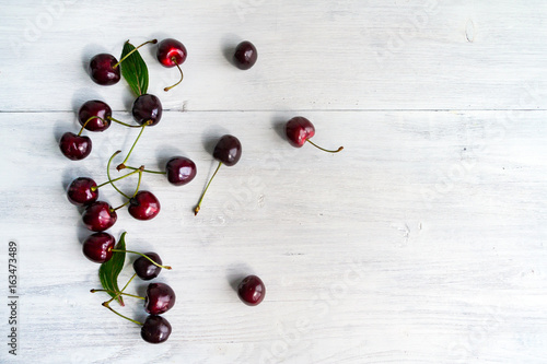 Summer food background - ripe cherry berries on white wooden table. Copy space.