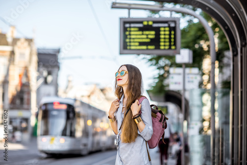 Foto Young woman standing on the tram station with time table in the old town of Gent