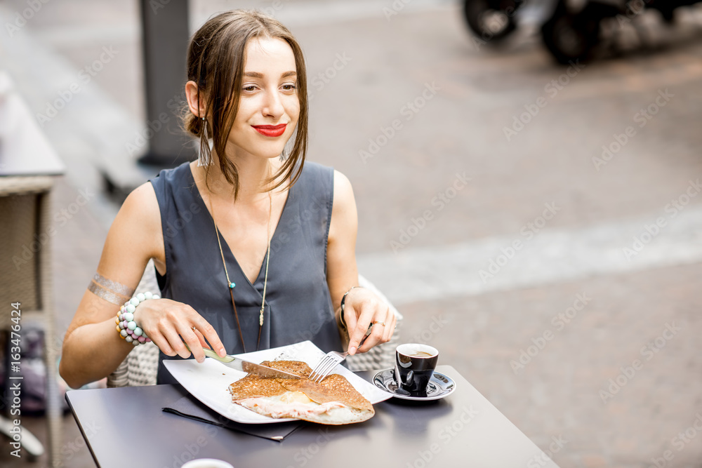 Young woman having a breakfast with french pancakes called galette sitting at the restaurant outdoors in Nantes city Young woman having a breakfast with french pancakes called galette sitting at the restaurant outdoors in Nantes city