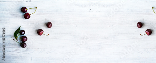 Summer food background - ripe cherry berries on white wooden table. Copy space. Wide panoramic image.