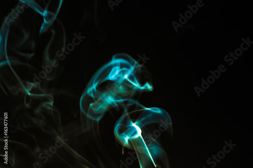 Smoke from burning incense sticks on dark background