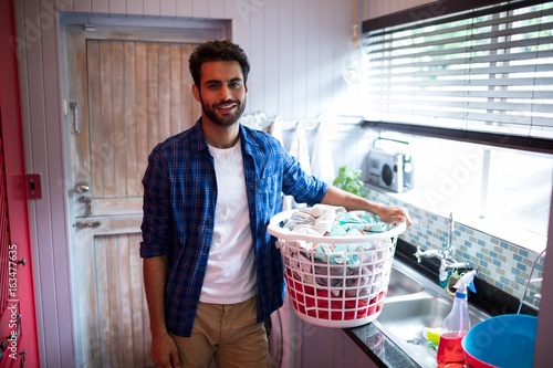 Portrait of young man holding laundry basket photo