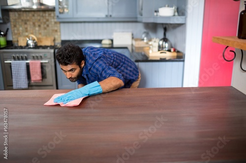 Young man cleaning table with napkin