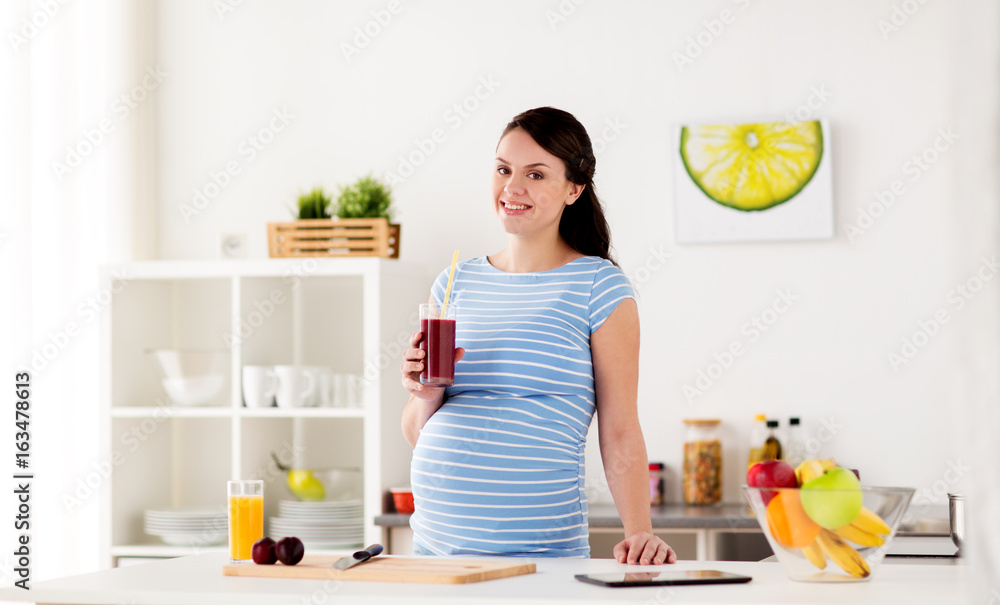 happy pregnant woman drinking juice at home
