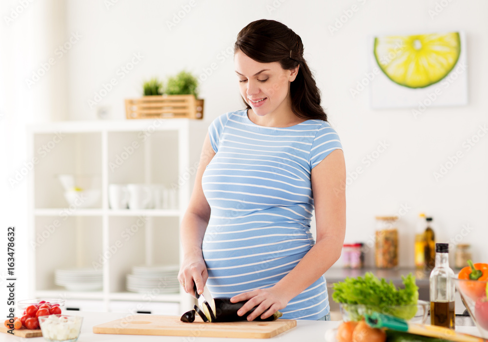 pregnant woman cooking vegetables at home