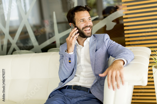Handsome young businessman using phone in office