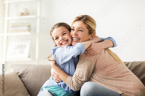 happy smiling family hugging on sofa at home