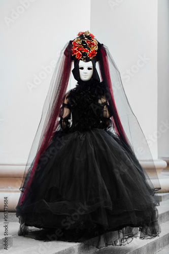 Witch portrait in black vintage dress, White mask covers face. Woman widow halloween.