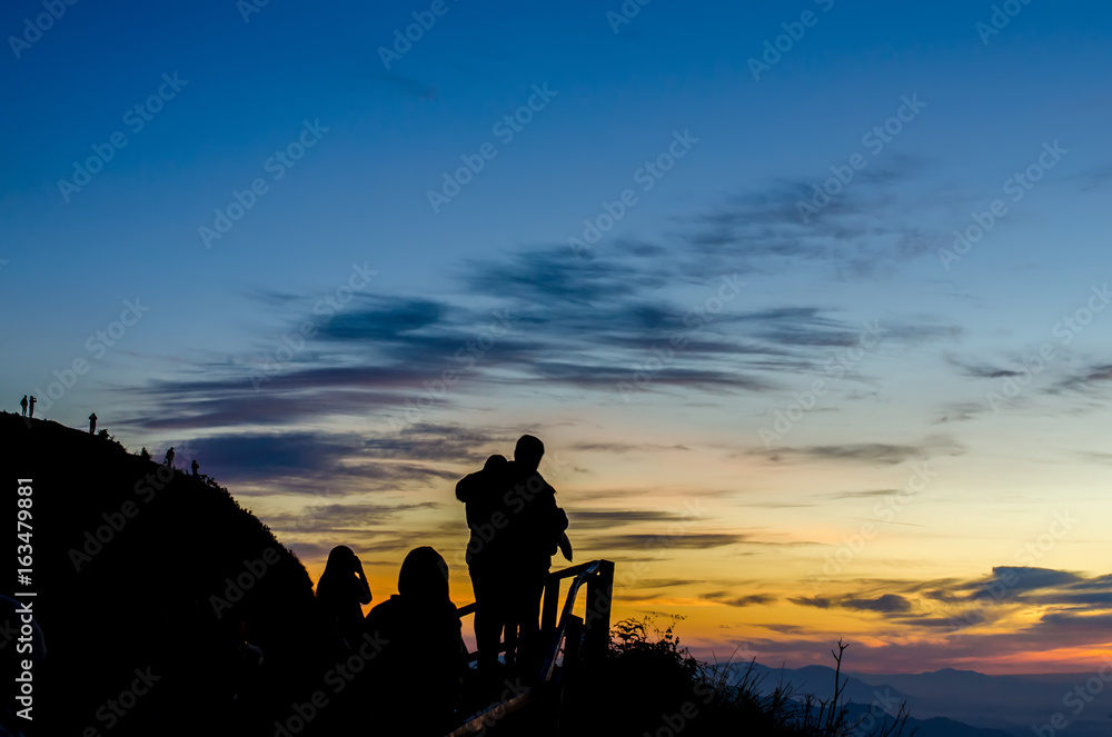 Silhouette of woman standing on the mountain against vivid sunset sky,located phu chi dao ,thailand.