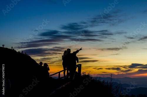 Silhouette of woman standing on the mountain against vivid sunset sky,located phu chi dao ,thailand.